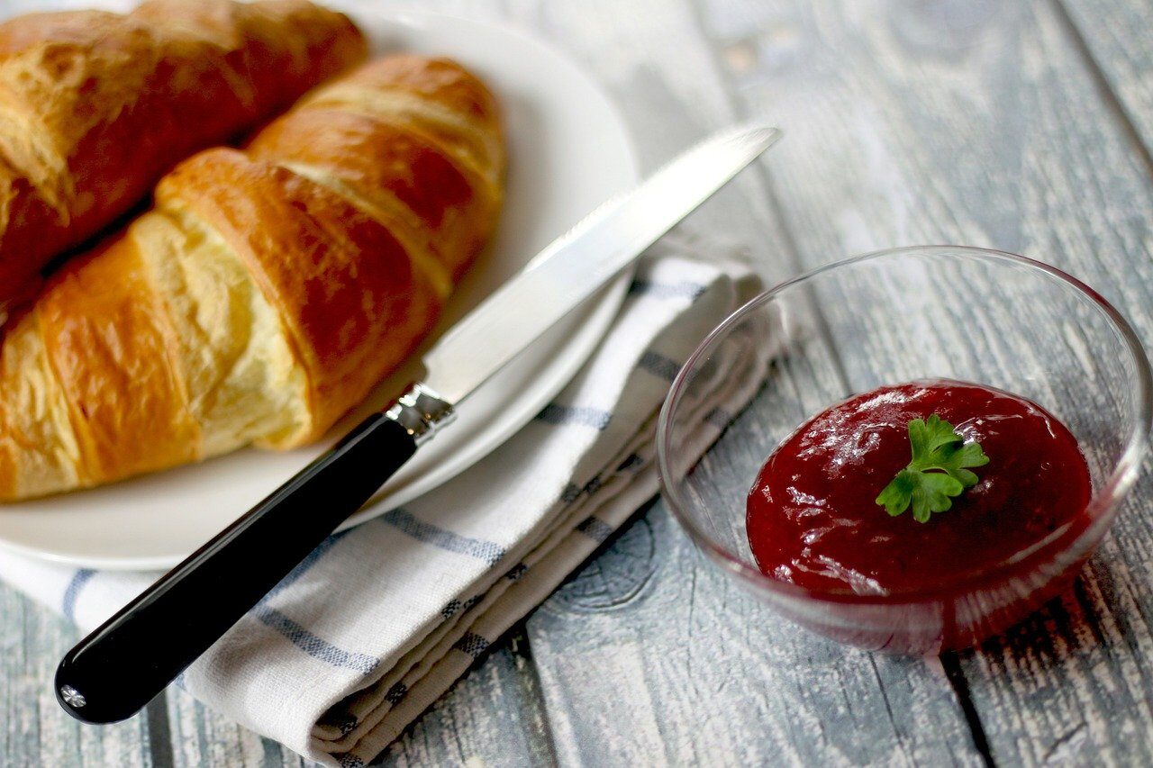 Croissants with butter and jam on a wooden table